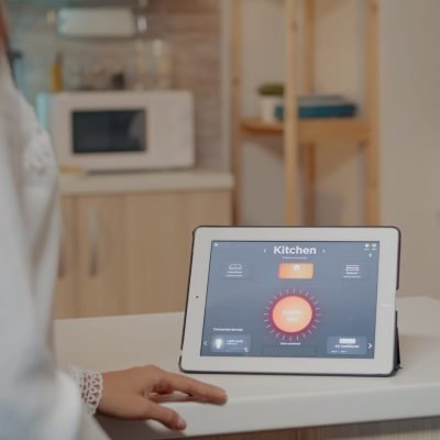 Young woman using smart home application with voice command to turn on the light by tablet. Lady using lighting control app in modern house with automation system controlling efficiency of energy